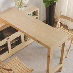 a wooden table with two chairs next to it and a potted plant in the corner