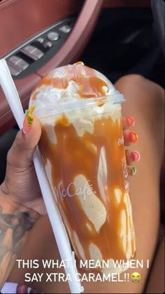 a woman holding up a cup with caramel and whipped cream on it in her hand