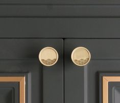 two gold knobs on the front of a black cabinet