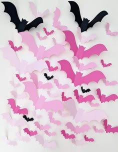 a group of bats flying through the air with pink and black paper cut outs on them