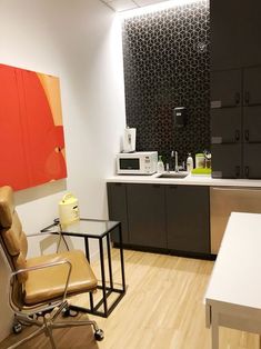 an office with a desk, chair and microwave on the wall in front of it