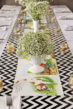 a long table with white flowers and place settings on it, along with silverware