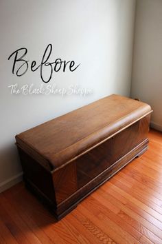 a wooden chest sitting on top of a hard wood floor next to a white wall