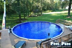 an above ground pool surrounded by decking and chairs in a backyard area with trees