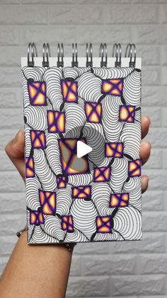 a hand holding up a spiral notebook with an abstract design on it