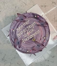 a birthday cake with purple frosting and butterflies on it sitting on a counter top