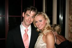 a man and woman are posing for a picture at a formal event in front of a window