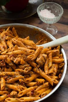 a bowl filled with pasta and sauce on top of a wooden table