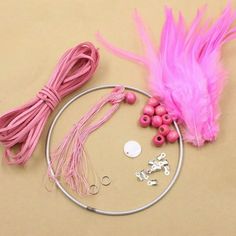 pink beads and other accessories are laid out on a table with a string, scissors, and thread