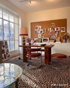 a living room filled with lots of furniture and pictures on the wall behind a glass table