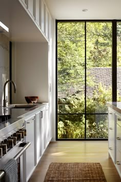 an open kitchen with sliding glass doors leading to the outside area and trees in the background