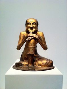 a golden buddha statue sitting on top of a white pedestal