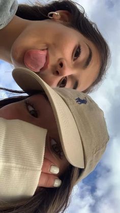 two women with hats on their heads are looking up into the sky and smiling at the camera