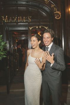 a man and woman standing next to each other in front of a hotel entrance at night