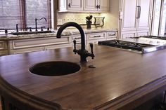 a kitchen with an island sink and stove top in the center, surrounded by white cabinets