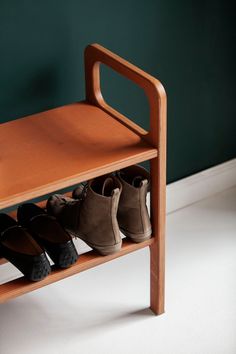 a wooden shoe rack with four pairs of shoes on it