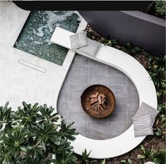 an aerial view of a garden with a fountain and water feature in the center, surrounded by greenery