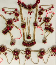 an assortment of red and gold necklaces with flowers on the sides, along with other jewelry pieces