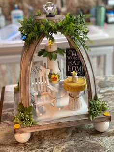 a miniature house made out of wood with plants on the front and sides, sitting on top of a table