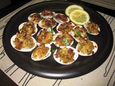 a black plate topped with deviled eggs and lemon wedges