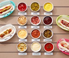 several different types of hot dogs and condiments in bowls on a wooden table