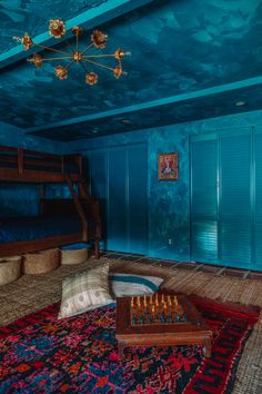 a bedroom with blue walls and carpeted flooring has a large rug on the floor