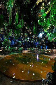 an outdoor venue with lots of green plants and lights hanging from the ceiling, surrounded by greenery