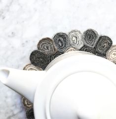 a close up of a white tea pot on a marble surface with black and grey circles