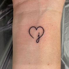 a small tattoo on the wrist of a woman with a musical note in the shape of a heart