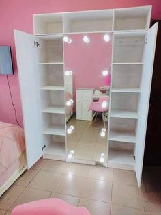 a pink room with white shelves and lights on the wall, in front of a bed