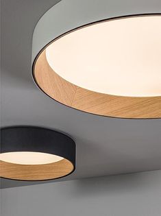 two circular lights hanging from the ceiling in a room with grey walls and wood accents