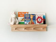 a wooden shelf filled with books and a stuffed animal on top of it next to a white wall