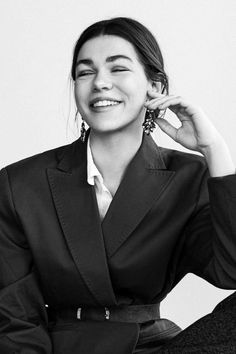 black and white photograph of a woman wearing a blazer with her hand on her ear