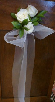 a bouquet of white roses tied to a wooden door