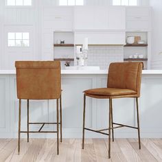 two brown leather chairs sitting on top of a wooden floor next to a kitchen counter