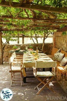 an outdoor dining area with tables and chairs under a pergolated roof, surrounded by greenery