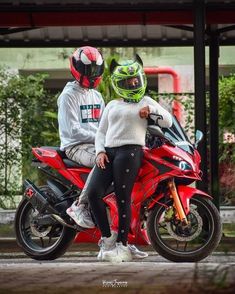 two people sitting on a red motorcycle