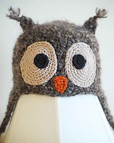 a crocheted owl hat on top of a white lamp with an orange nose