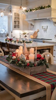 a christmas centerpiece with candles and ornaments in it on a kitchen countertop next to a dining room table