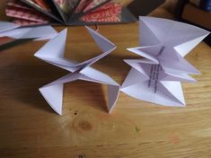 two origami flowers sitting on top of a wooden table