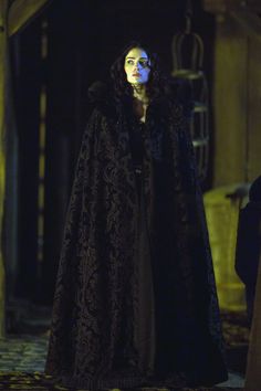 a woman dressed in black and wearing a cloak