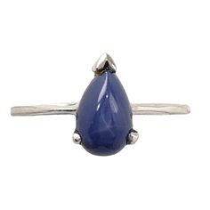 a silver ring with a blue tear shaped stone on the front and side, set against a white background