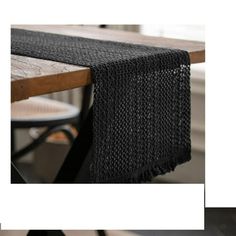 the table runner is made out of black woven material and sits on top of a wooden table