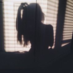 the shadow of a woman standing in front of a door with her hair pulled back