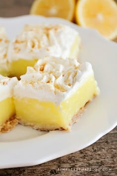 three slices of lemon meringue pie on a white plate with sliced lemons in the background