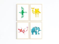 four framed art pieces with different colored animals on white wall above chair and table in room