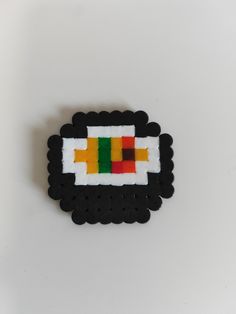 a piece of art made out of black and white beads with an orange, green, yellow and red design on it