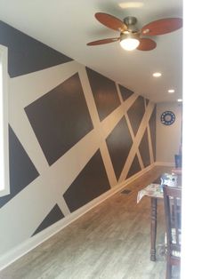 an empty room with black and white wallpaper, ceiling fan and wooden flooring