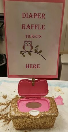 an open pink case sitting on top of a table next to a sign that says diaper raffle tickets here