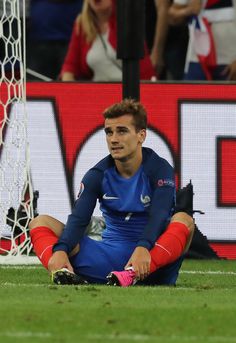 a man sitting on the ground in front of a soccer goal